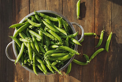 High angle view of green peas on wooden table