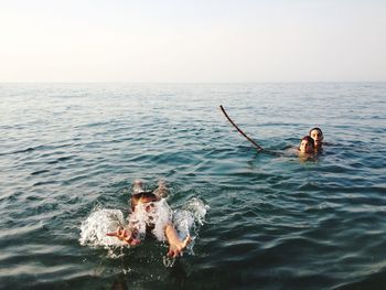 Children in sea against clear sky