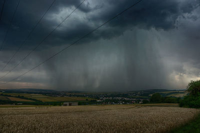 Scenic view of field against storm clouds