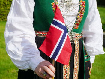 Midsection of woman wearing traditional clothing while holding norwegian flag