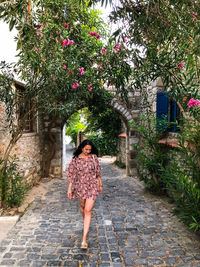 Young candid millennial woman is walking by cobbled street in bodrum in a summer silk mini dress