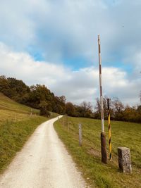 Empty road amidst field against sky