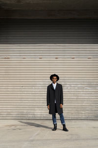 Full length portrait of man standing against wall