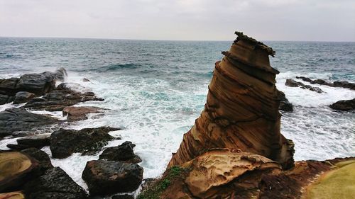 Scenic view of rocks in sea against sky