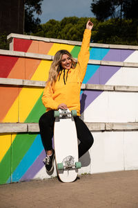 Portrait of a cheerful woman with a skateboard on colorful stairs