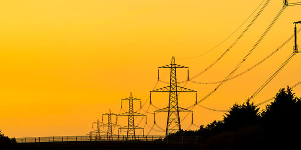 Low angle view of silhouette electricity pylon against romantic sky