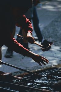 Cropped image of person washing hands using water and ladle