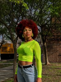 Portrait of young woman standing against trees