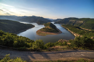 Scenic view of lake by mountains against sky