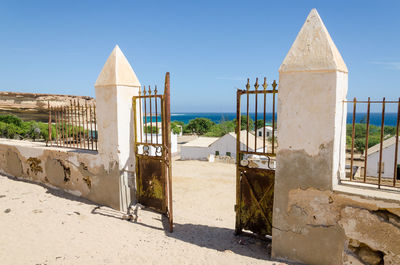 Old wall and fence of colonial building against clear blue sky, mucuio, angola