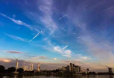 Cranes in city against sky during sunset