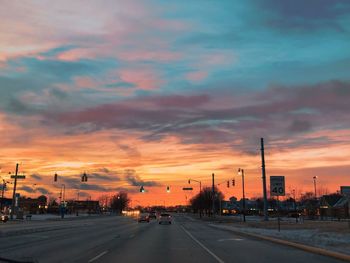 Road passing through city during sunset