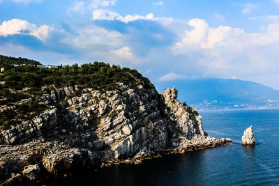 Scenic view of sea by mountain against sky