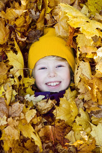 Portrait of happy girl surrounded by autumn leaves