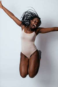 Portrait of young woman jumping against white background
