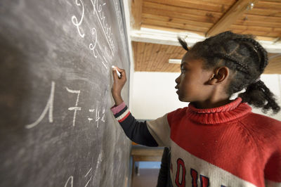 Madagaskar, girl in fianarantsoa elementary school calculatiing at blackboard