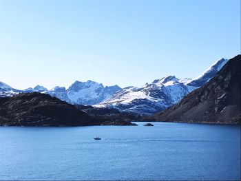 Scenic view of lake and mountains against clear blue sky