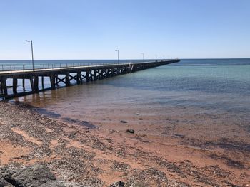 Pier on beach against clear sky