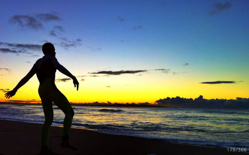 Silhouette people on beach at sunset