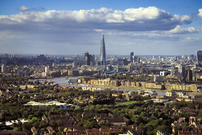 Aerial view of city buildings against cloudy sky