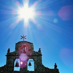 Low angle view of sun shining through clouds