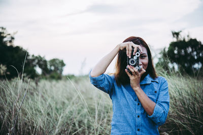 Man photographing on field against sky