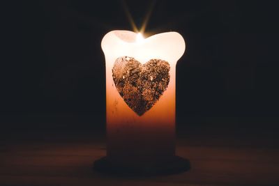 Close-up of lit candle on table against black background