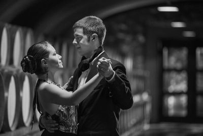 Side view of young couple dancing in room