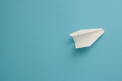 Plane made of white paper on a blue background, minimalism