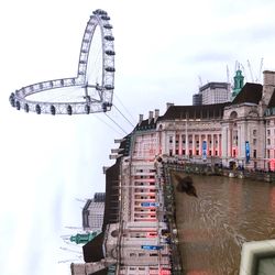 Low angle view of ferris wheel against buildings in city