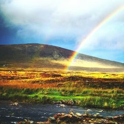Scenic view of rainbow over lake against sky