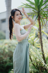 Portrait of young woman standing against plants