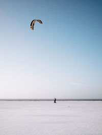 Person kiteboarding on snowcapped beach during winter