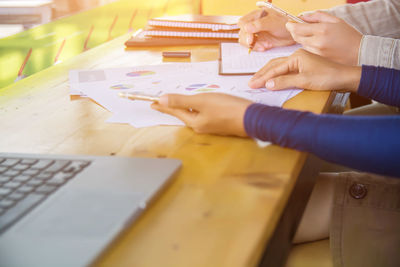 High angle view of woman holding paper on table