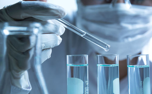 Midsection of scientist with liquids doing experiment in laboratory