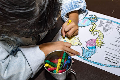 High angle view of boy holding toy on table