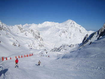 People skiing in mountains against clear sky