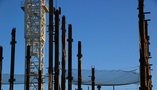 Low angle view of industry against clear blue sky