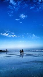 Two people on horses on beach
