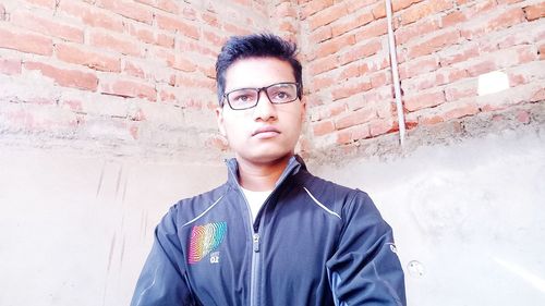 Portrait of young man standing against wall