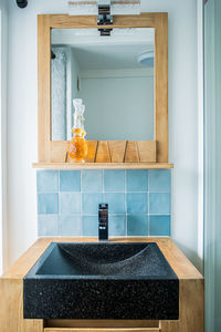 Wooden cabinet with sink at wall with mirror in light bathroom with toilet and window