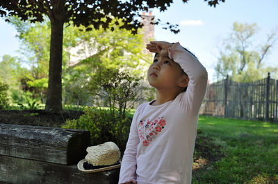 Boy looking away while standing by plants