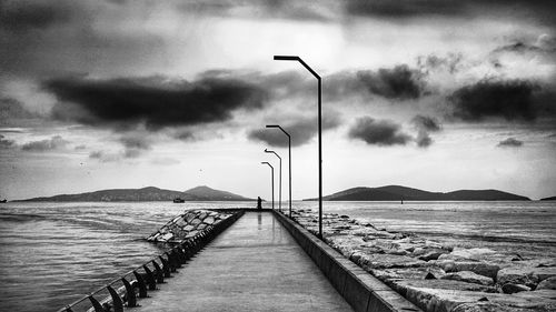 Pier on sea against cloudy sky