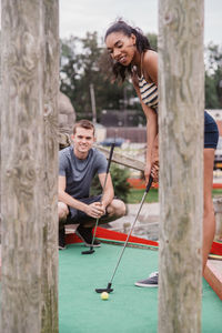 Portrait of young couple standing on tree trunk