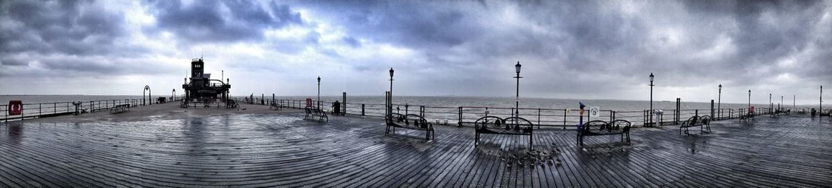 Pier on sea against cloudy sky