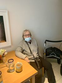 Senior woman wearing masks sitting by table