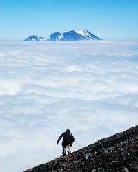 High angle view of man climbing mountain against cloudy sky