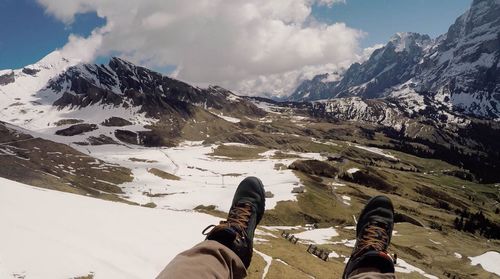 Low section of man on snowcapped mountains against sky