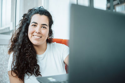 Portrait of young woman using mobile phone while sitting on table