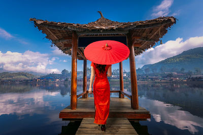 Rear view of man standing by lake against sky